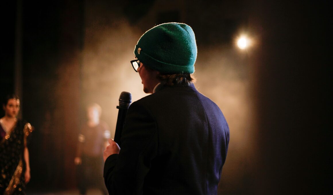 Moody scene of a performer holding a microphone under a spotlight on stage.