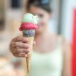 Woman holding a vibrant ice cream cone topped with sprinkles, creating a refreshing summer treat.