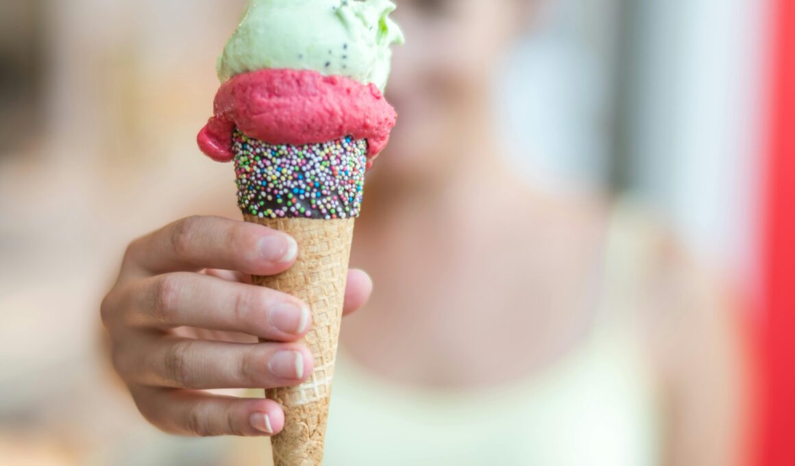 Woman holding a vibrant ice cream cone topped with sprinkles, creating a refreshing summer treat.