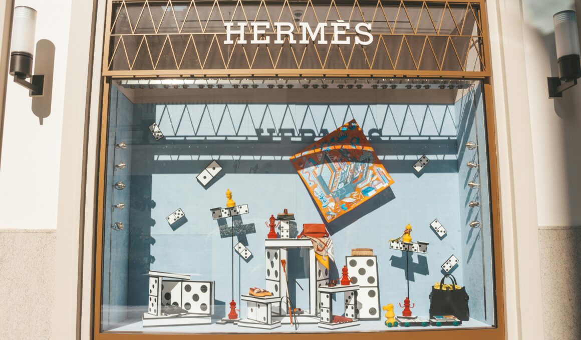 Artistic window display at a Hermes store featuring domino-themed decor and luxury items.
